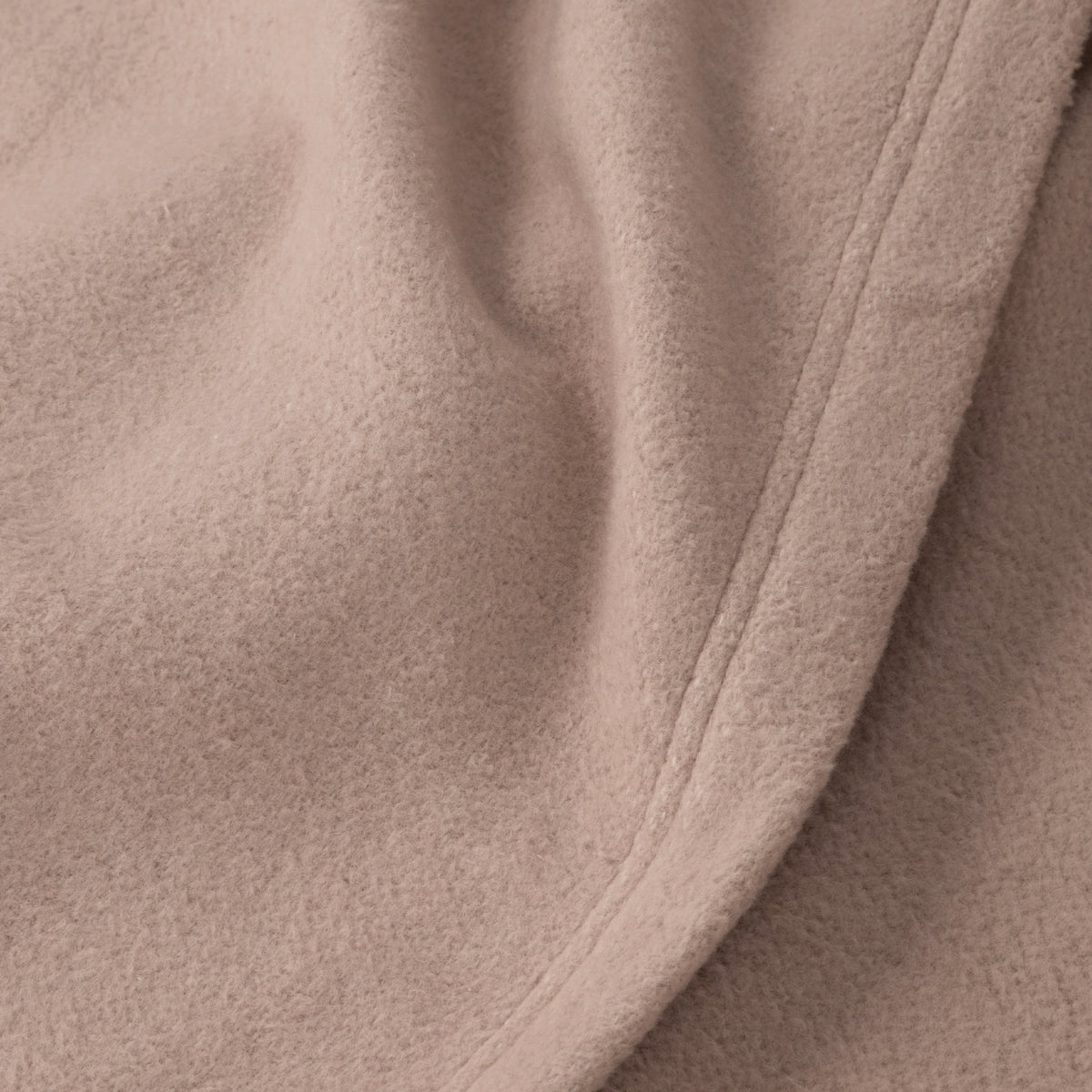 Taupe blanket fabric close-up with stitched edge