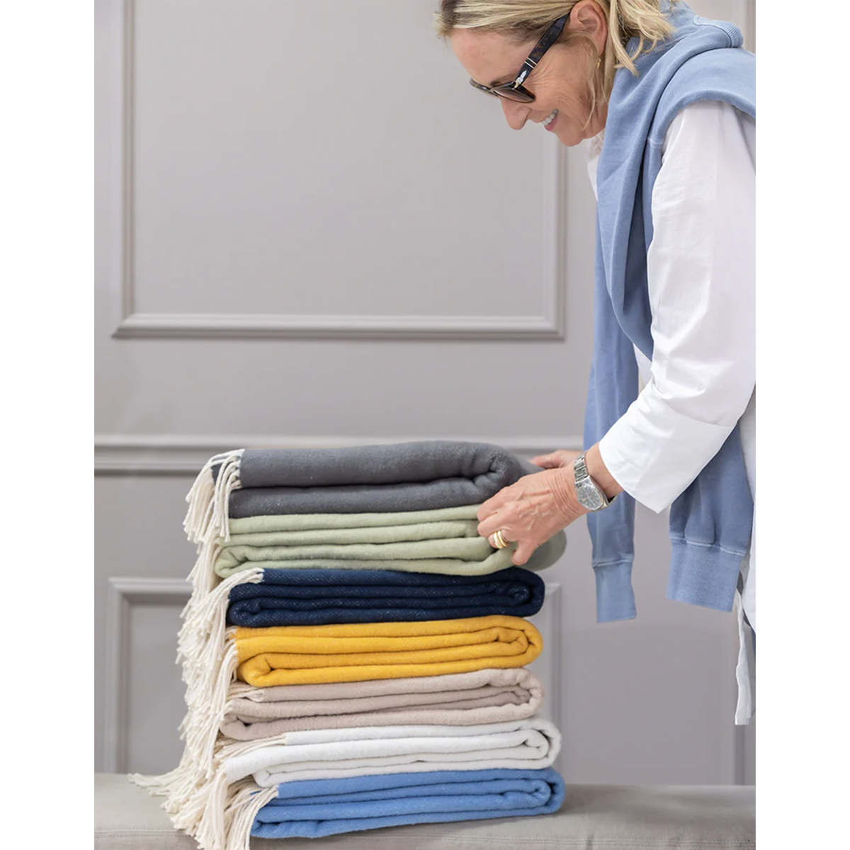 Stack of folded throw blankets with fringed edges in multiple colors