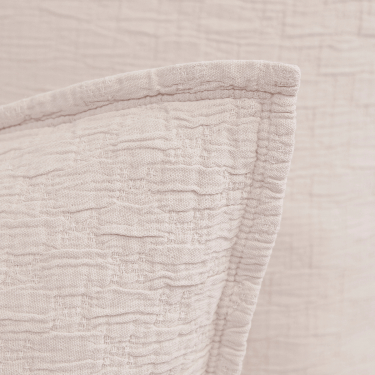 Matelasse pillow sham corner close-up in light blush with raised stitched texture