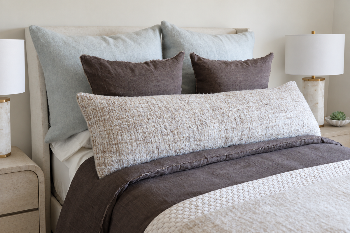 18x60 body pillow in ivory with speckled fabric on a bed