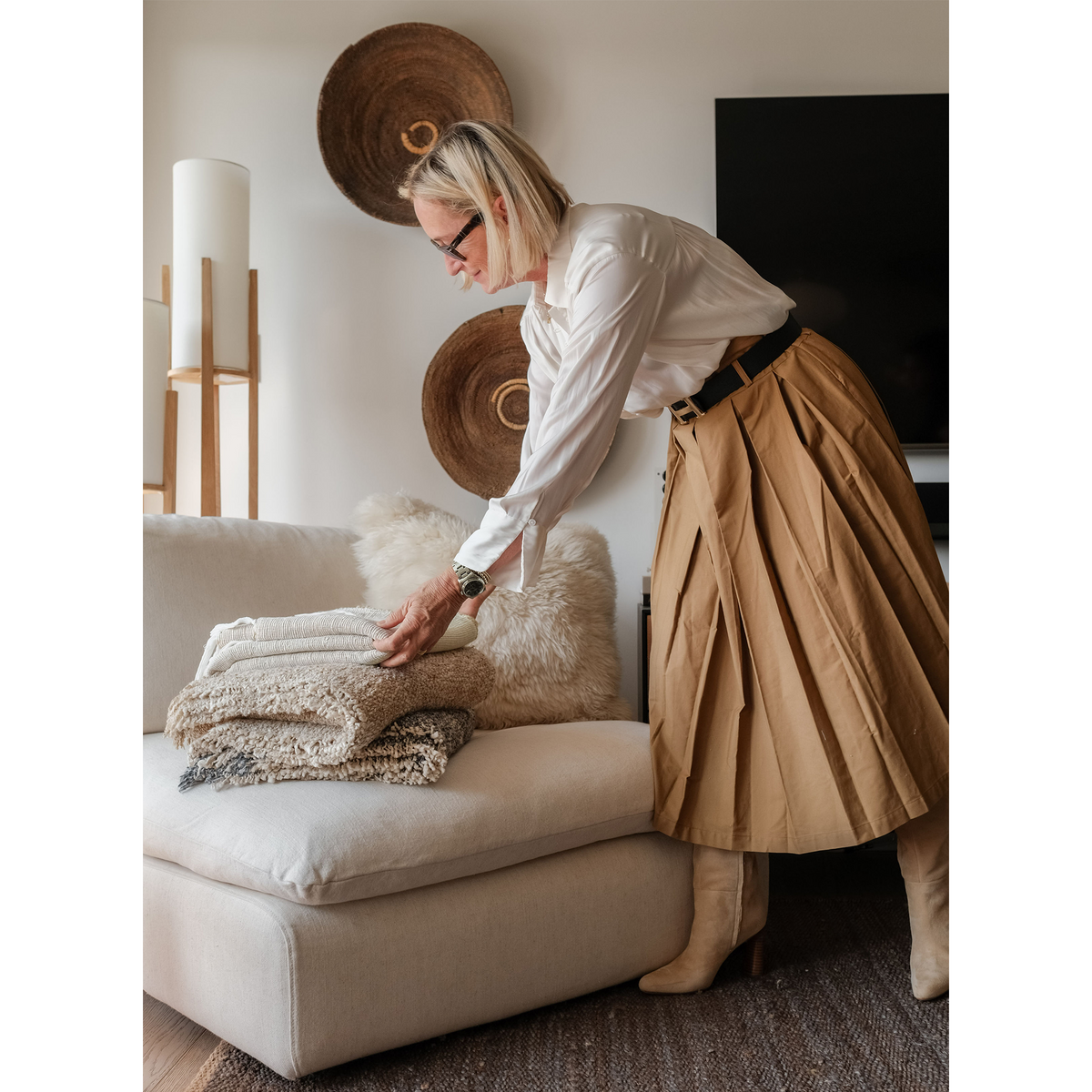 Folded woven throw blanket in cream with fringed edge on a sofa seat
