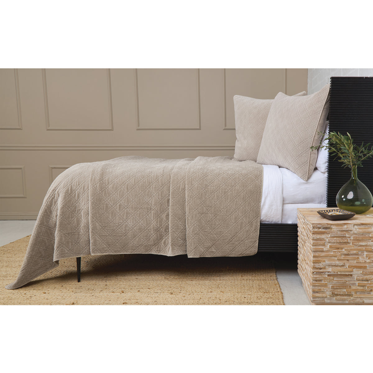 Light taupe quilted coverlet with diamond pattern on a bed with beige pillows