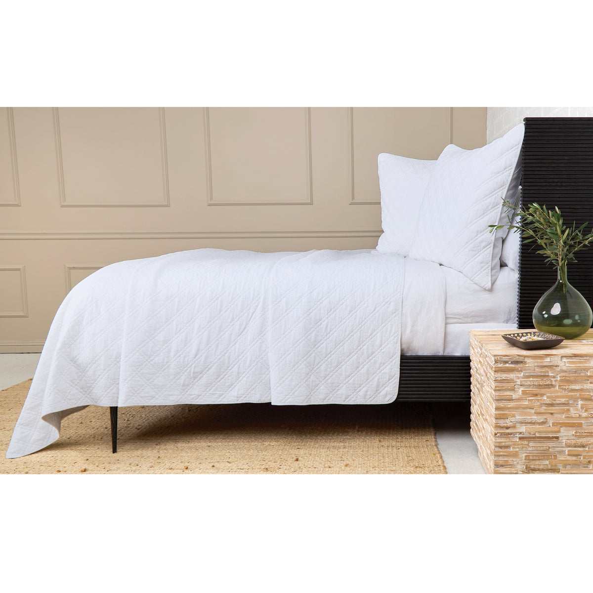 White quilted coverlet with diamond pattern on a bed with white pillows