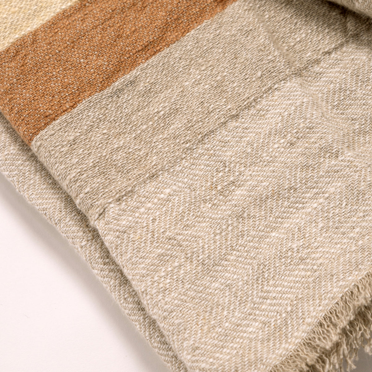 Beige textured woven throw blanket with multicolor stripes and fringed edge detail.