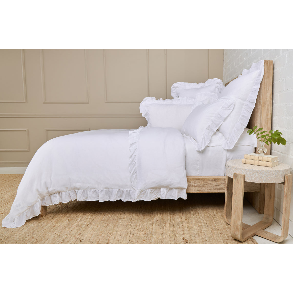 White duvet cover with layered ruffled shams on bed with pillows