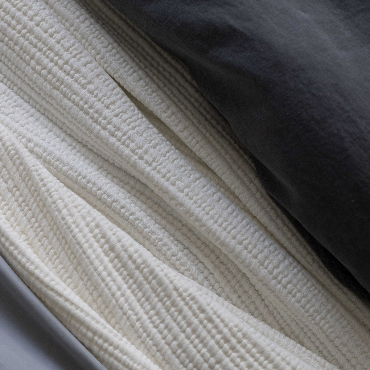 Oversized throw blanket in cream with close-up of raised fabric texture.