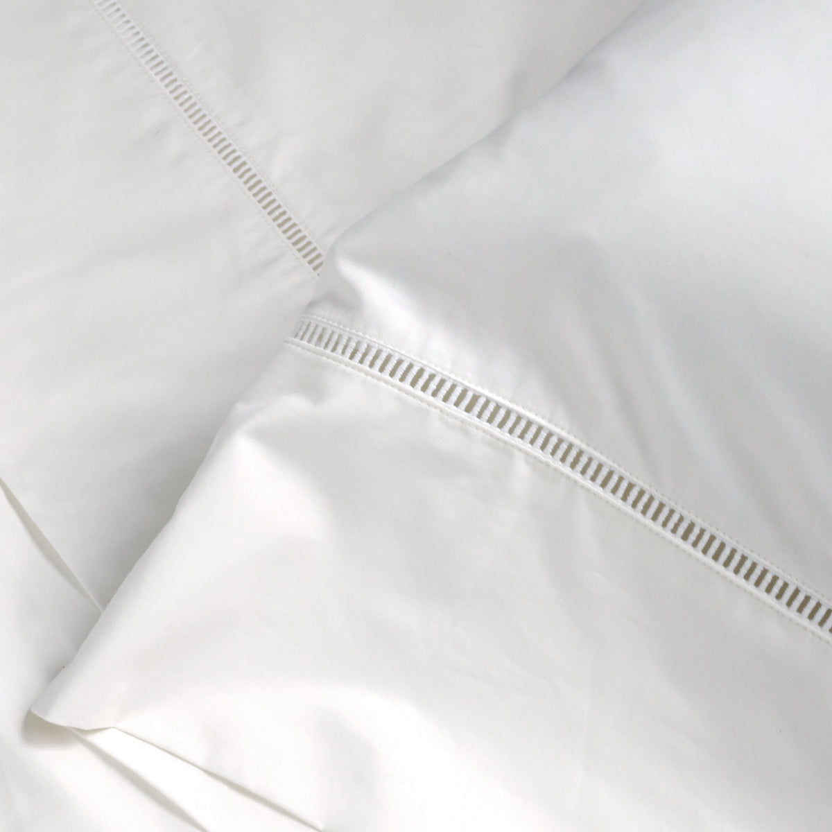White pillowcase with ladder-stitched border near the seam and piped edge