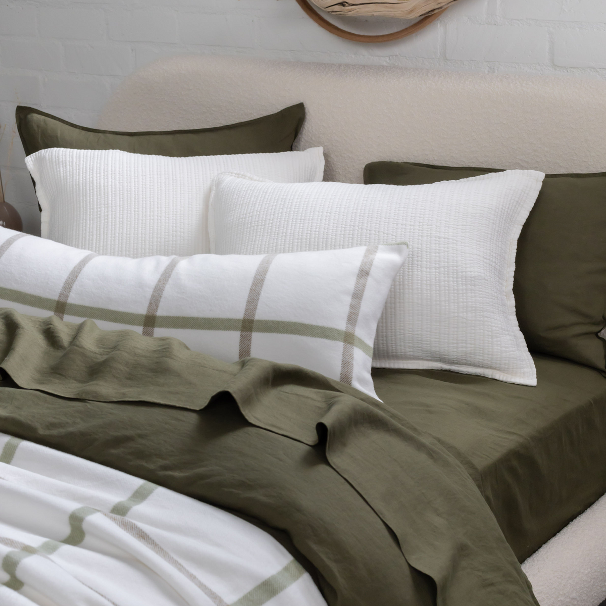Plaid throw blanket on bed, white base with light gray and olive grid pattern