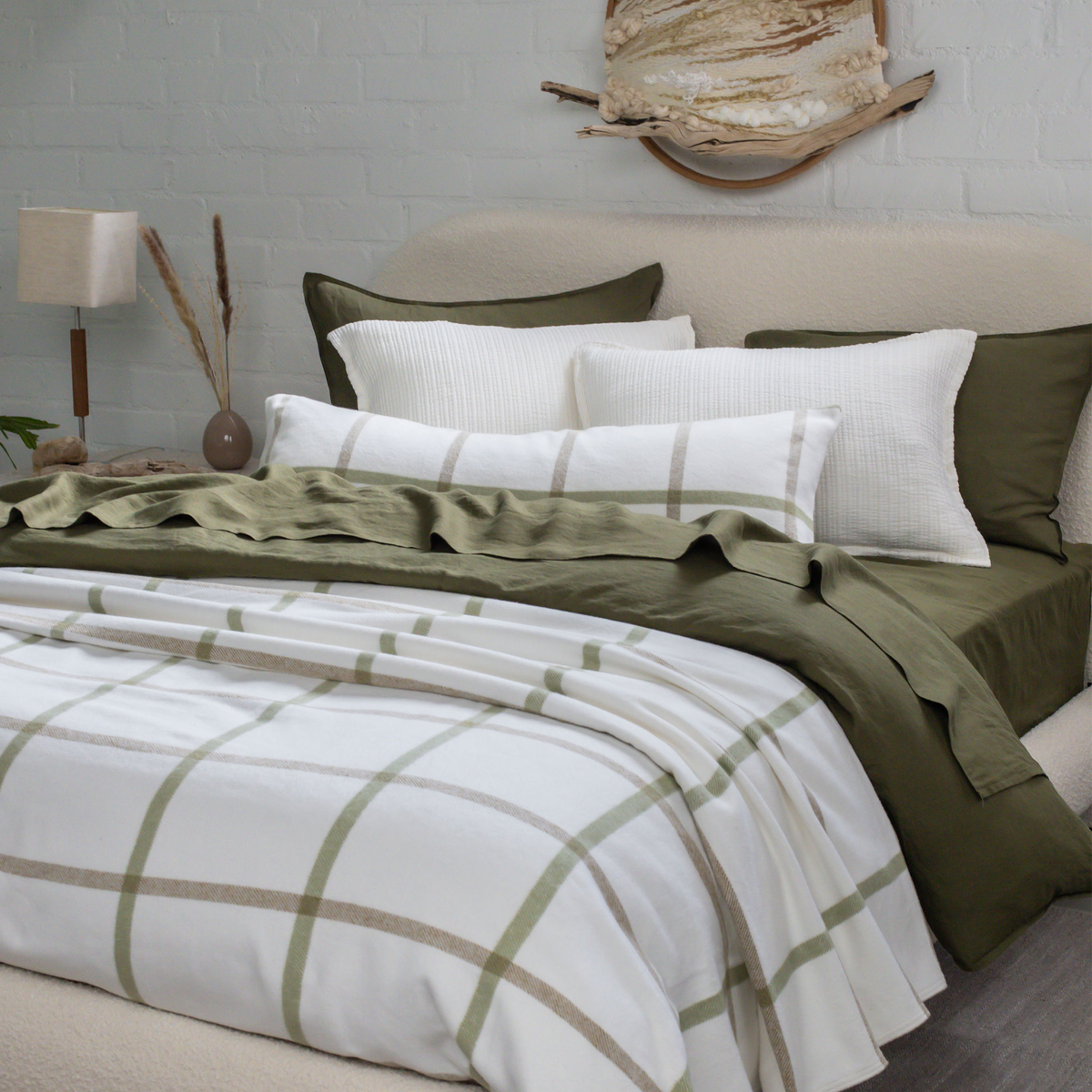 Plaid throw blanket on bed, white with green grid lines over dark green duvet