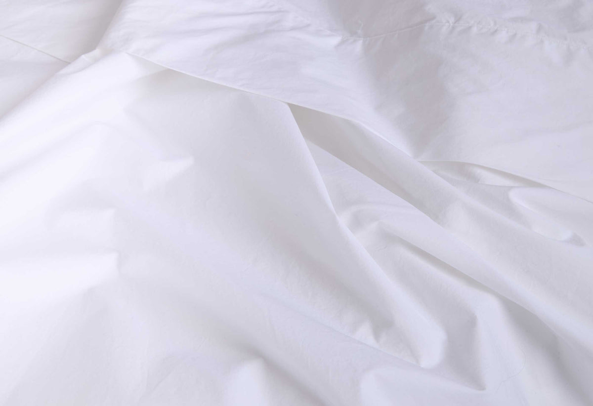 White cotton percale flat sheet with subtle folds and crisp texture
