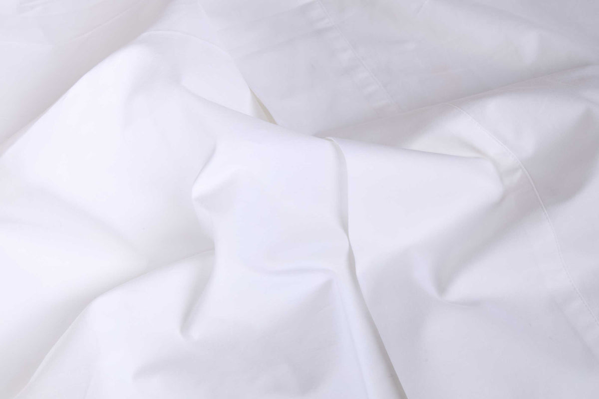 White cotton sateen sheet fabric close-up showing smooth weave and folds