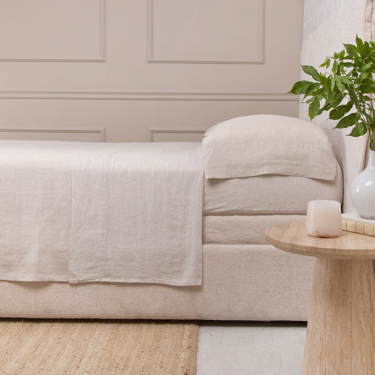 Cream linen sheet set on sofa, draped flat sheet and folded pillowcase