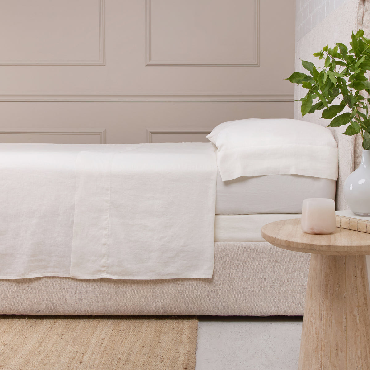 White linen sheet set on sofa, flat sheet draped over seat with pillowcase