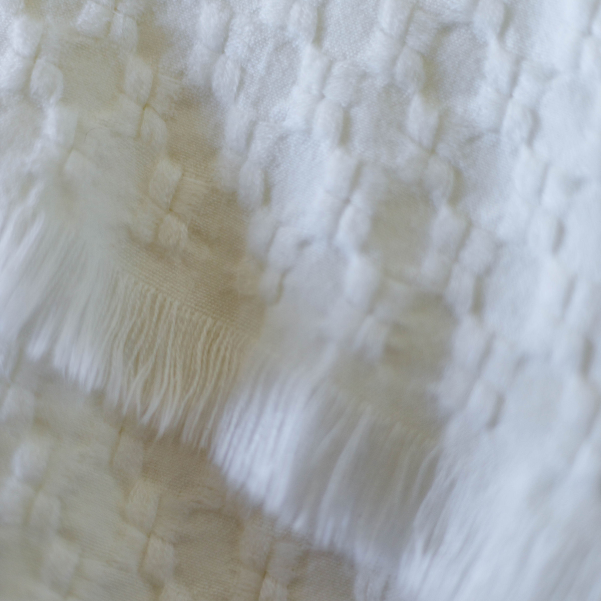 Delphine oversized throw close-up in ivory with woven grid texture and fringe detail