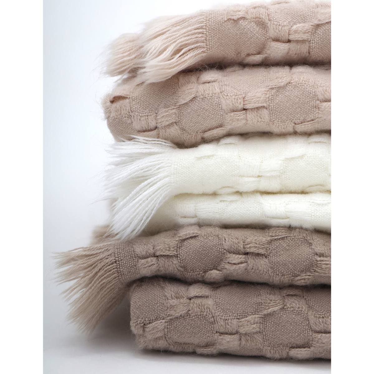 Delphine oversized throw stack showing blush, ivory, and taupe with fringed edges