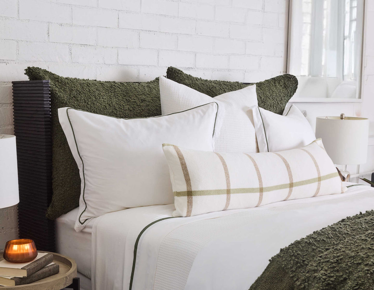 Oversized throw in moss green with textured knit on a white bed