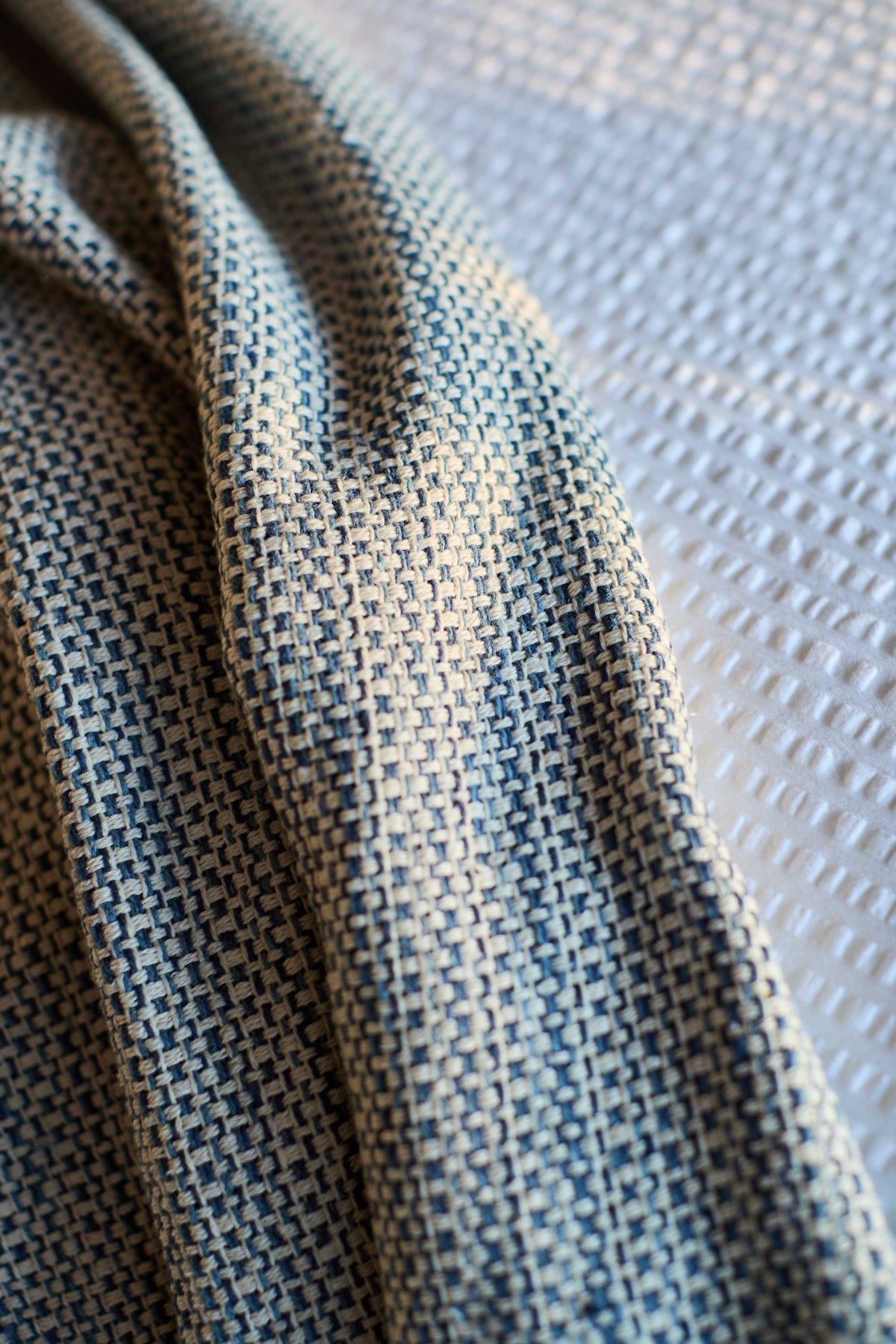 Close-up of blue-grey woven throw fabric with textured grid pattern