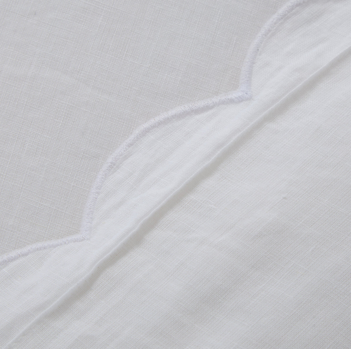 White fabric detail with subtle white scalloped piping edge