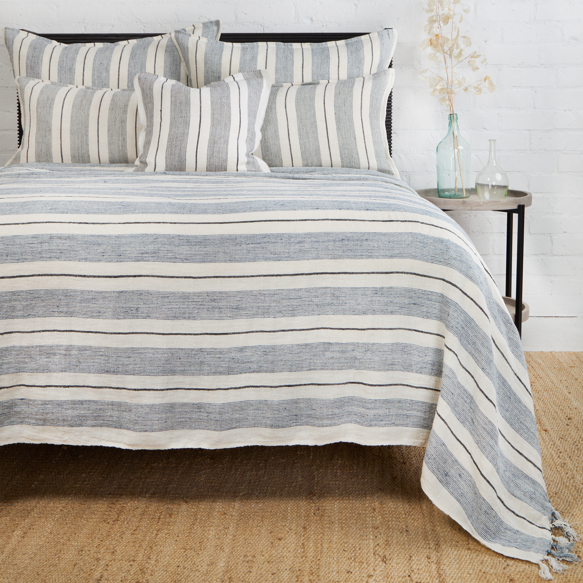 Laguna striped throw blanket in blue and white with fringed edge draped over bed