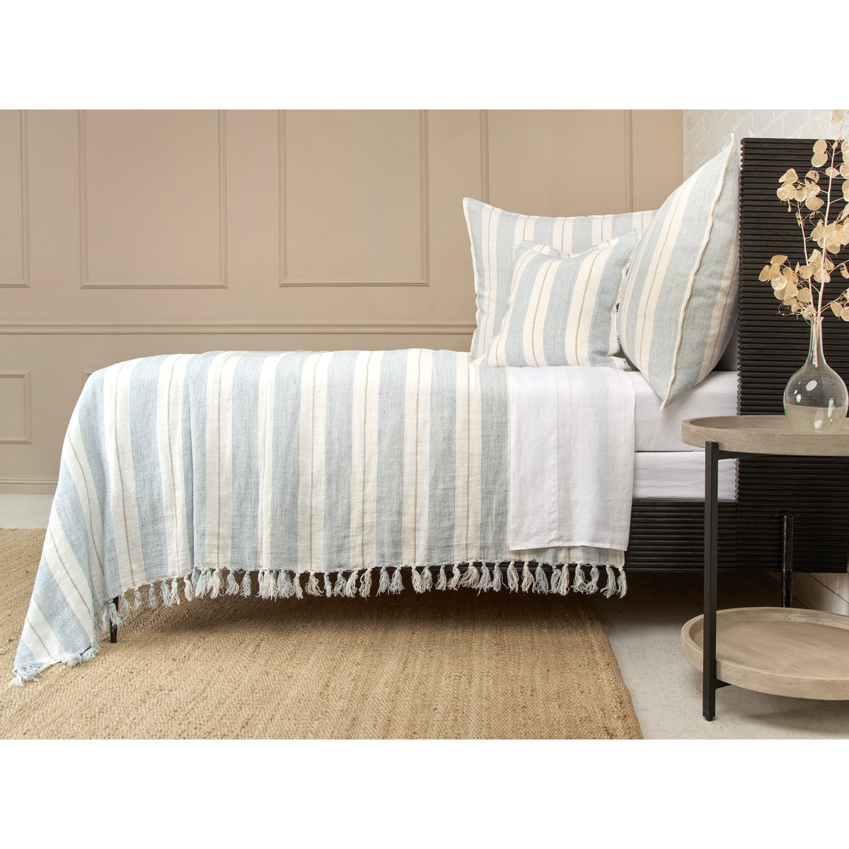 Grey and natural striped blanket with tassel fringe across the bed