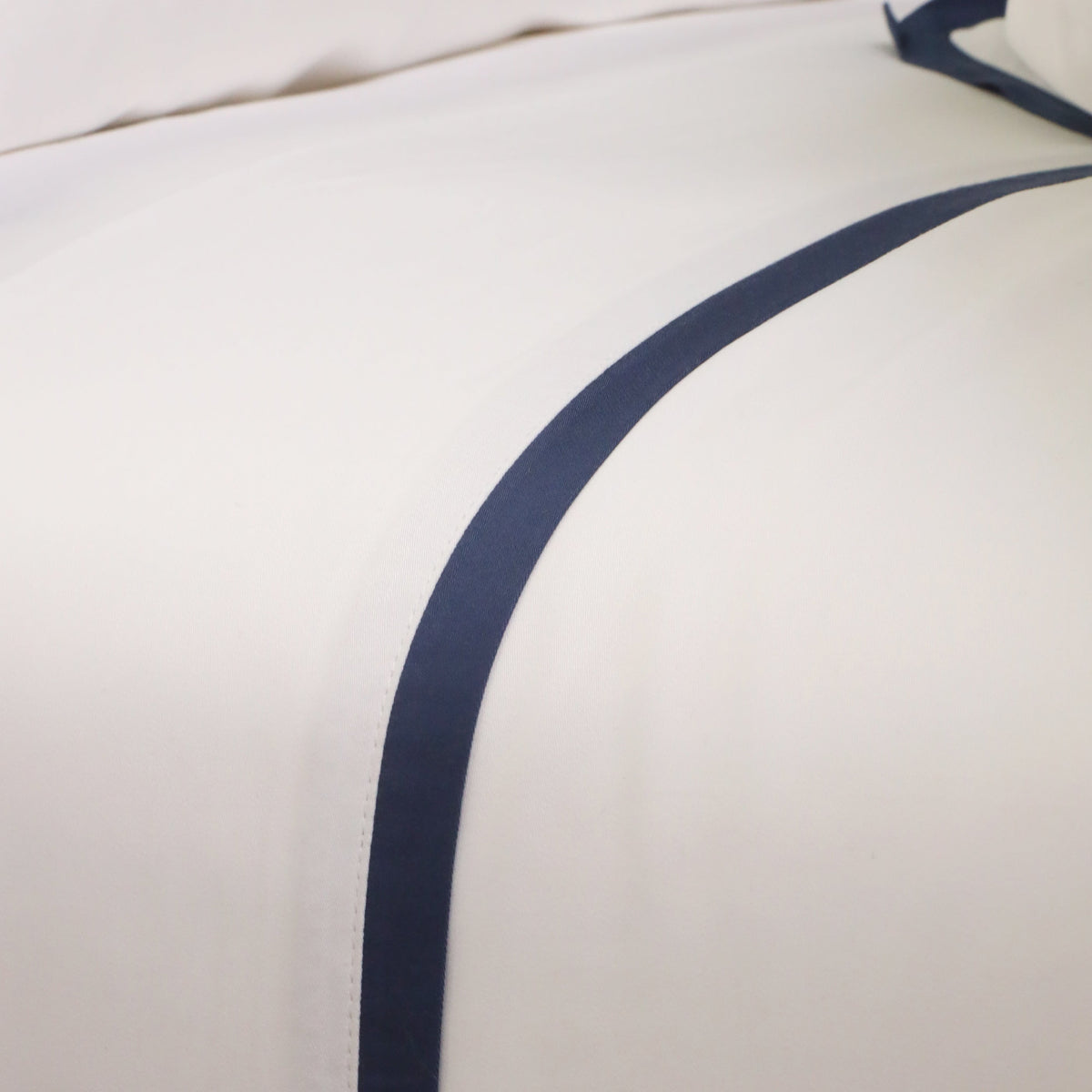 Close-up of white duvet with navy border piping seam
