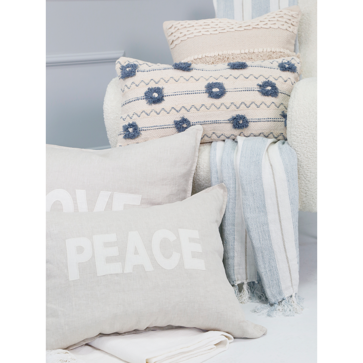 Laguna striped blanket with light blue and white bands and fringed trim on pillows