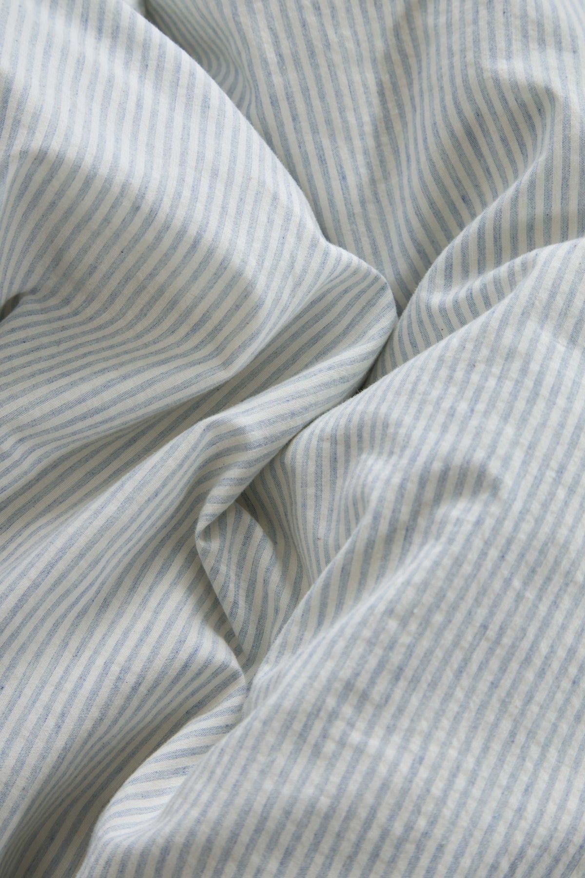 Light blue striped duvet cover fabric with soft woven texture and folds