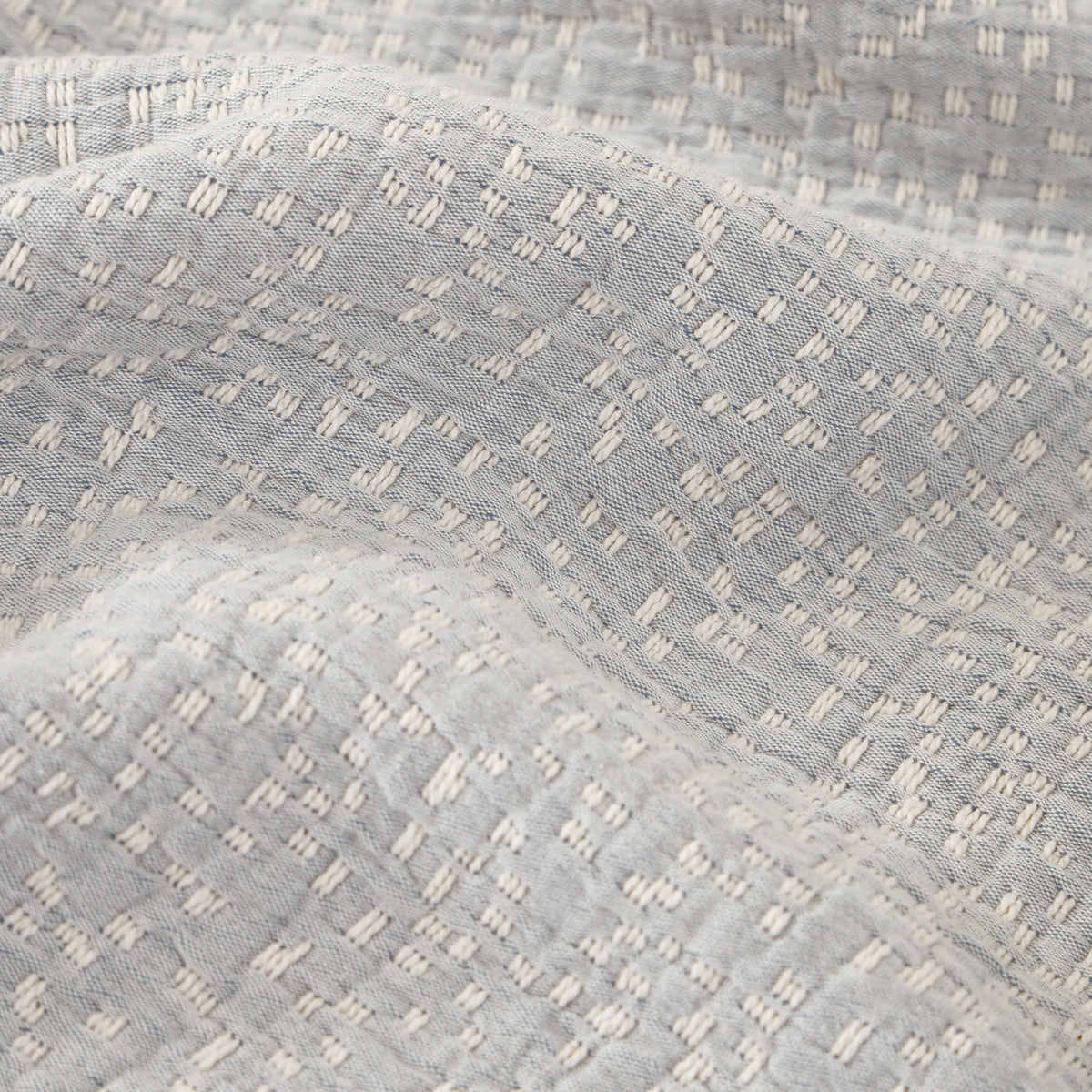 Light blue matelasse textured fabric swatch with raised geometric stitch pattern