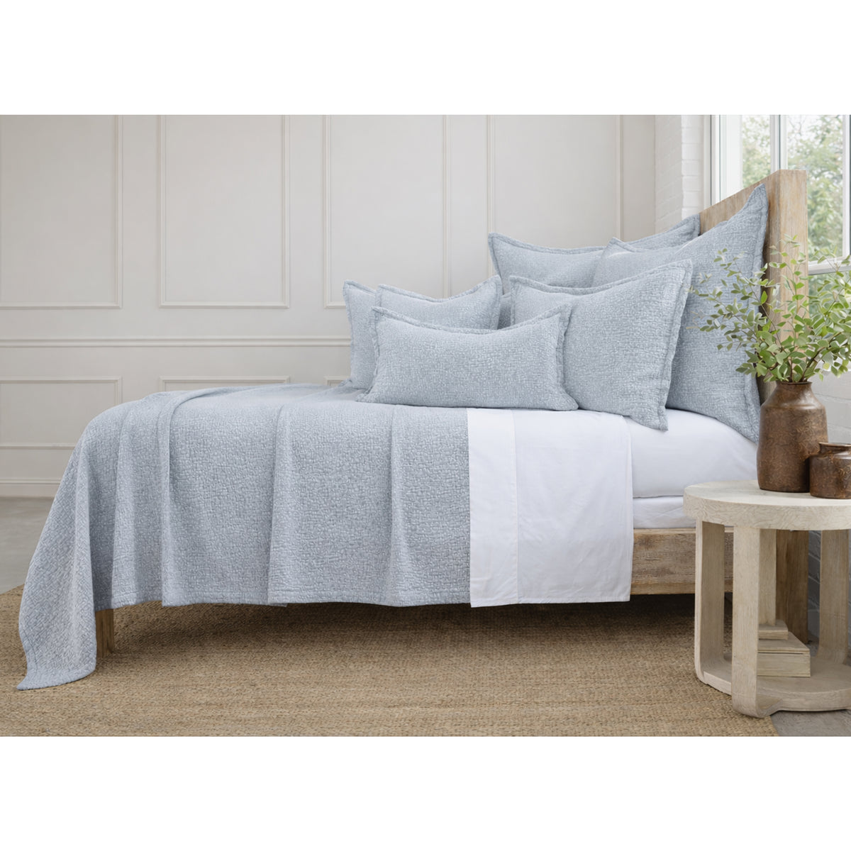 Light blue matelasse bed quilt with matching pillow shams, textured woven surface