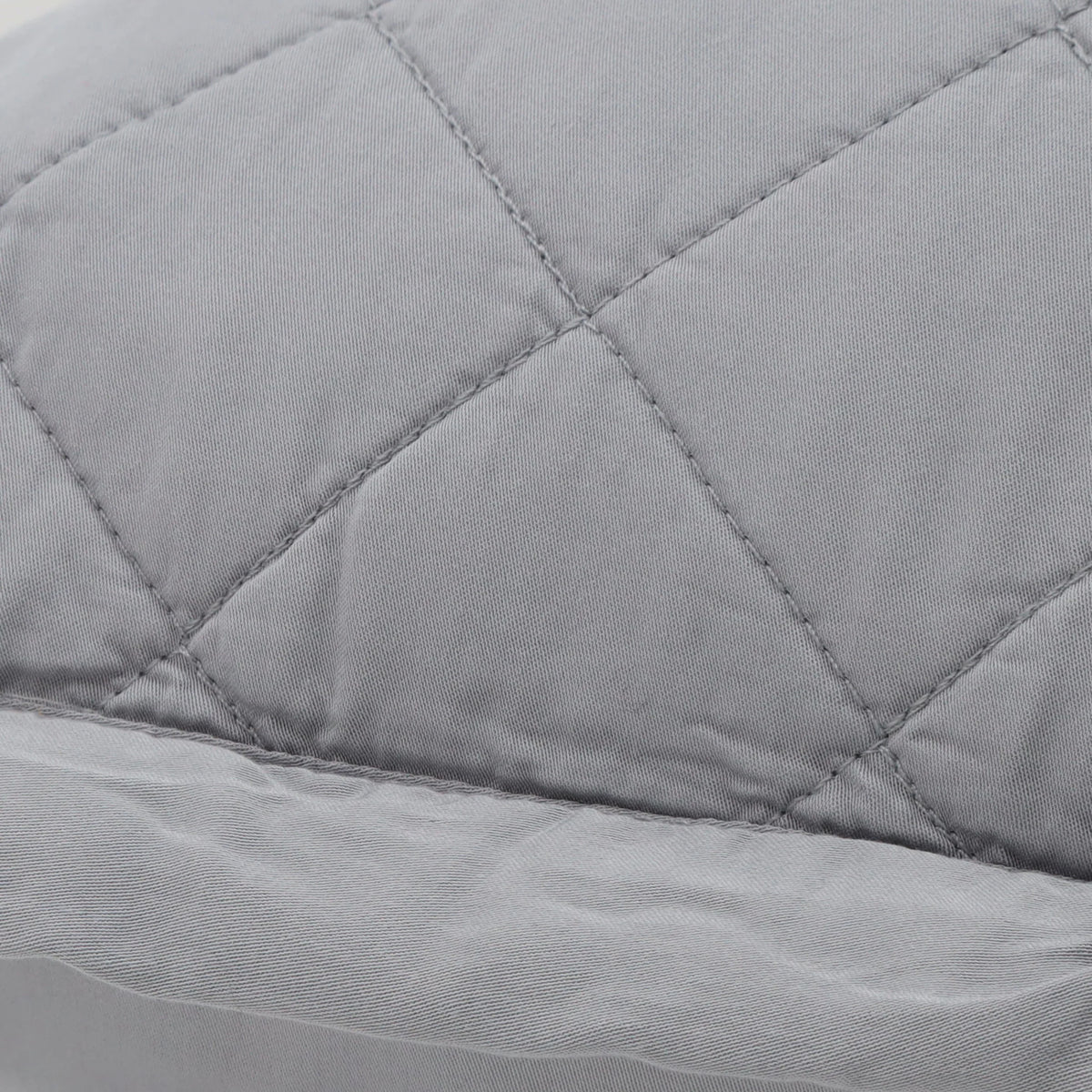 Close-up of quilted diamond stitch on a light gray pillow cover with edge trim.