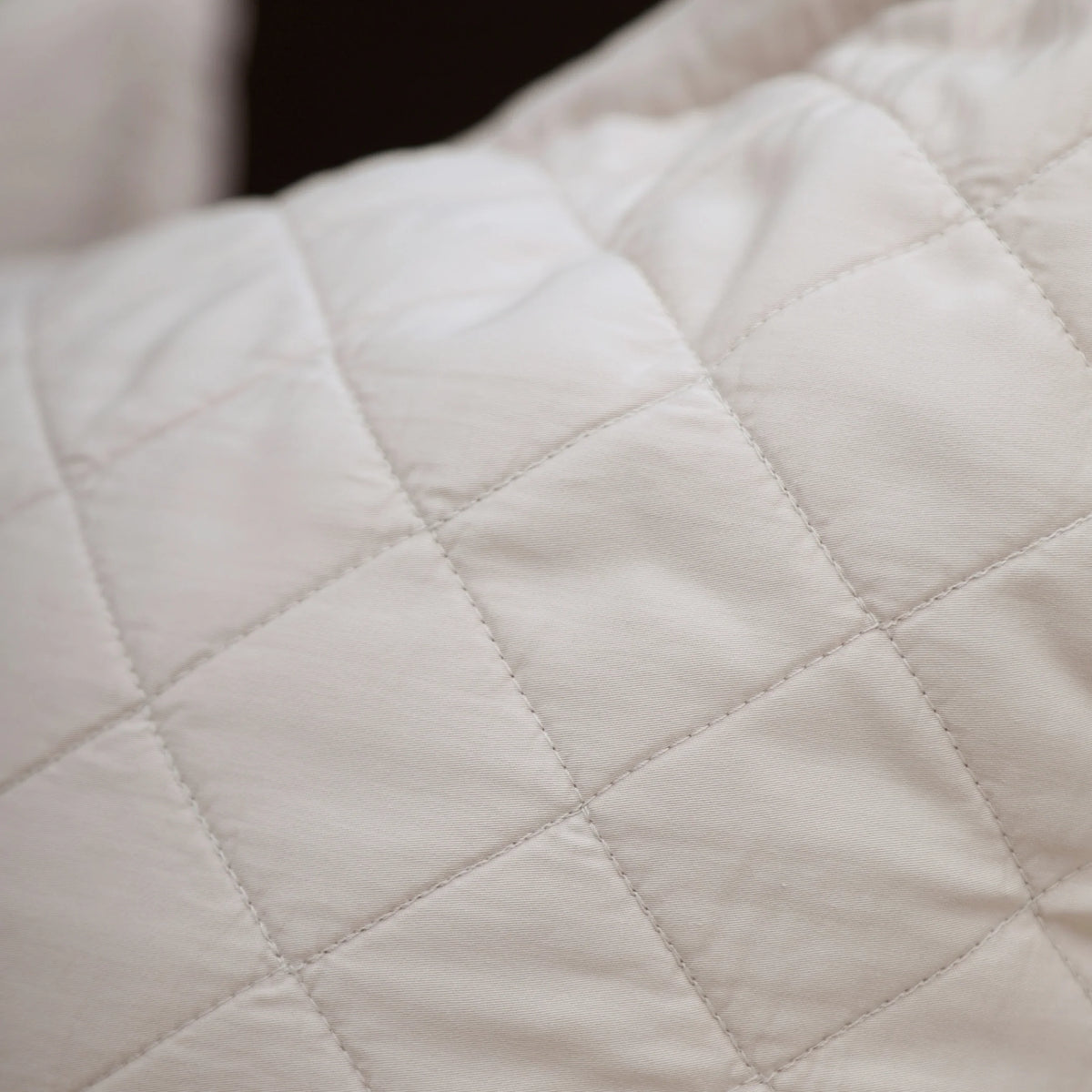 Quilted diamond stitch detail on a white pillow cover with stitched seams.