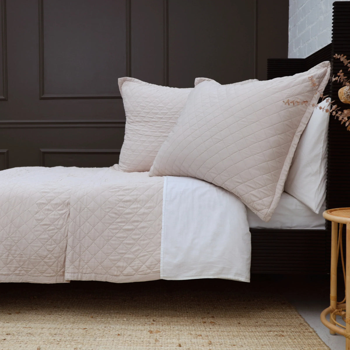 Rectangular white big pillow with stitched diamond pattern with matching pillows on bed.