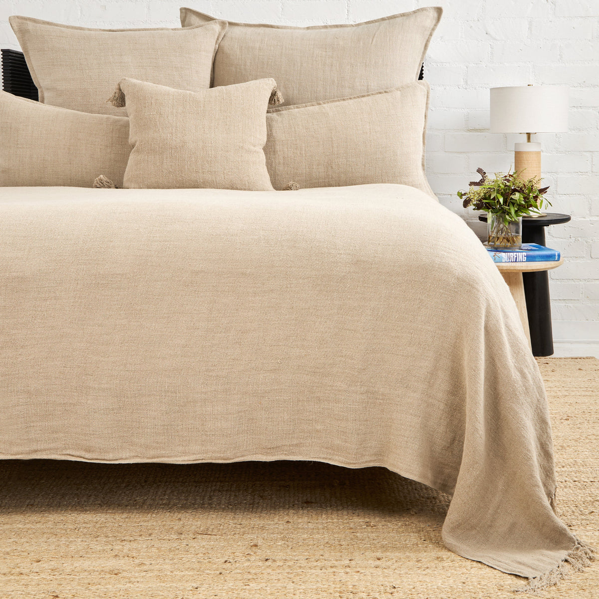 Natural cream textured blanket with fringed edge draped over bed