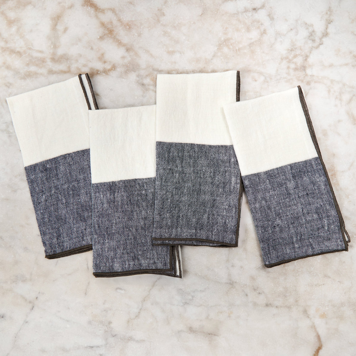 Two-tone napkin set in white and gray with dark stitched border, folded squares
