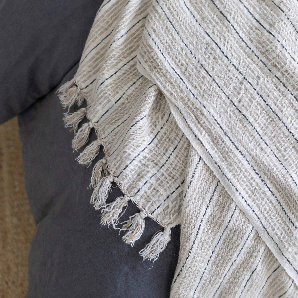 Close-up striped throw with light beige vertical lines and knotted fringed trim