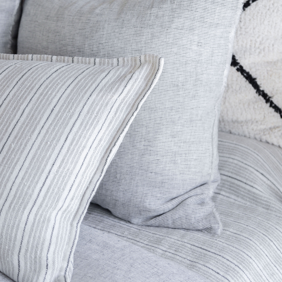 Striped pillow insert close-up with light gray fabric and stitched seam