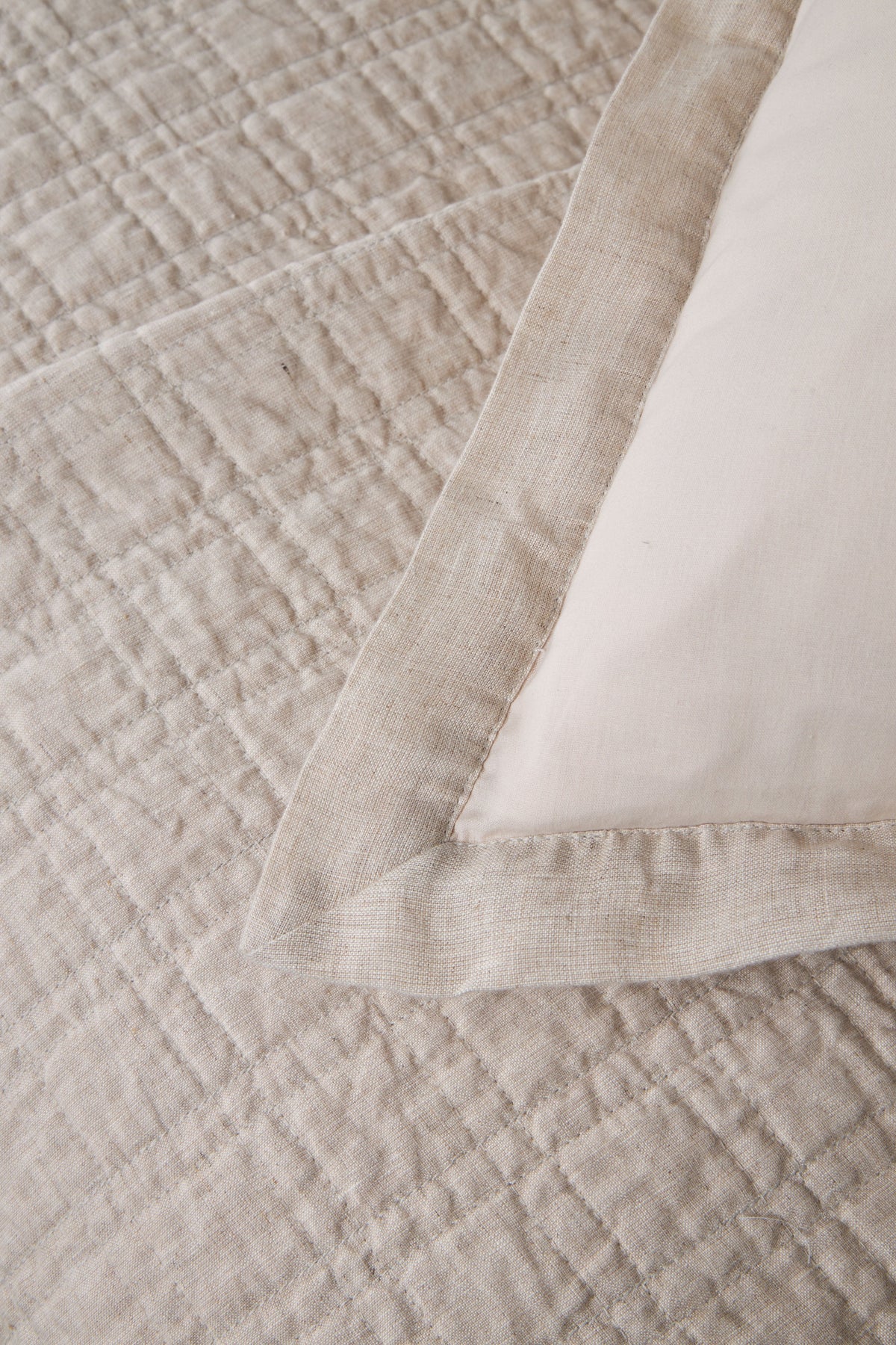 Owen coverlet corner with light cream quilted weave and folded edge