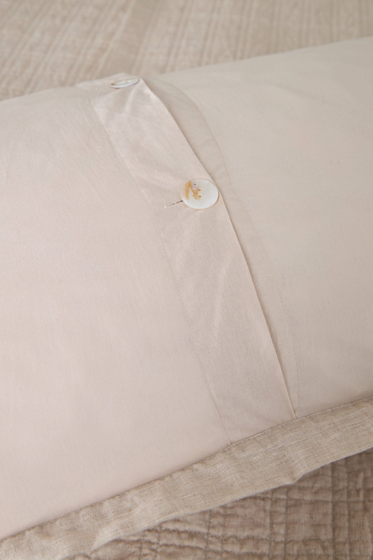 Owen coverlet corner detail with button closure and quilted light cream fabric
