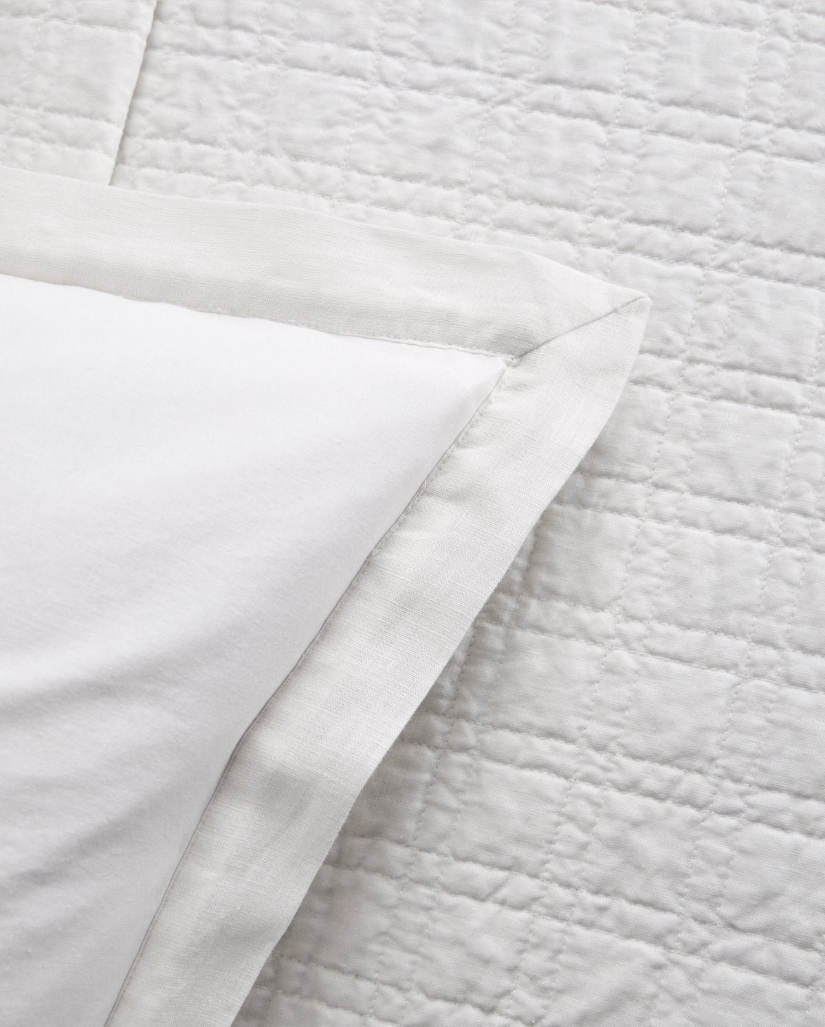 Owen coverlet in white showing stitched border and layered fabric corner