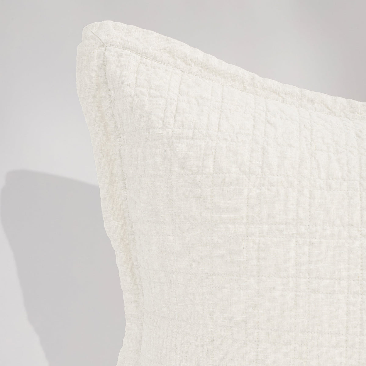 Owen coverlet in white with subtle grid quilting and soft, draped edge