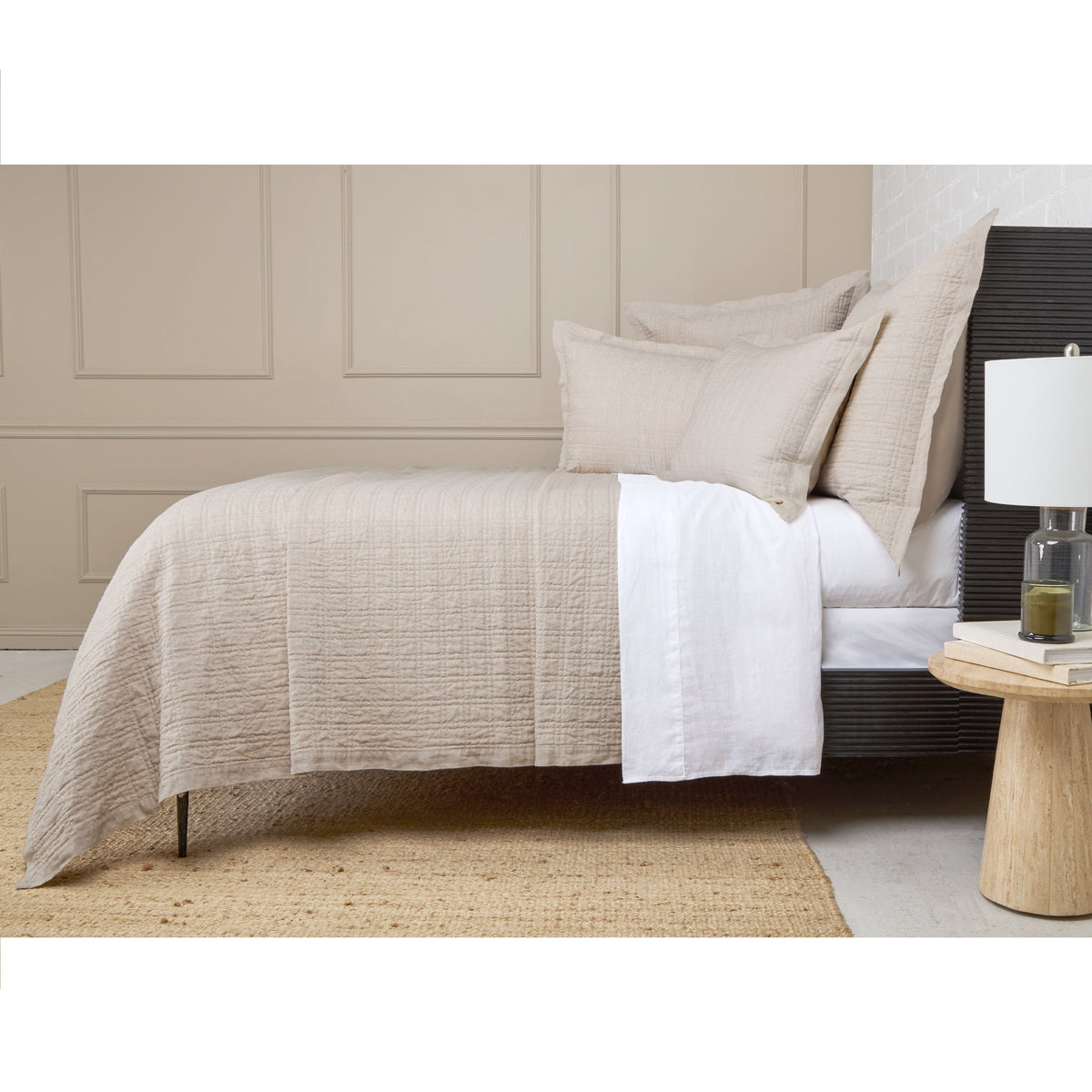 Owen coverlet in light cream on bed with quilted texture and stitched border