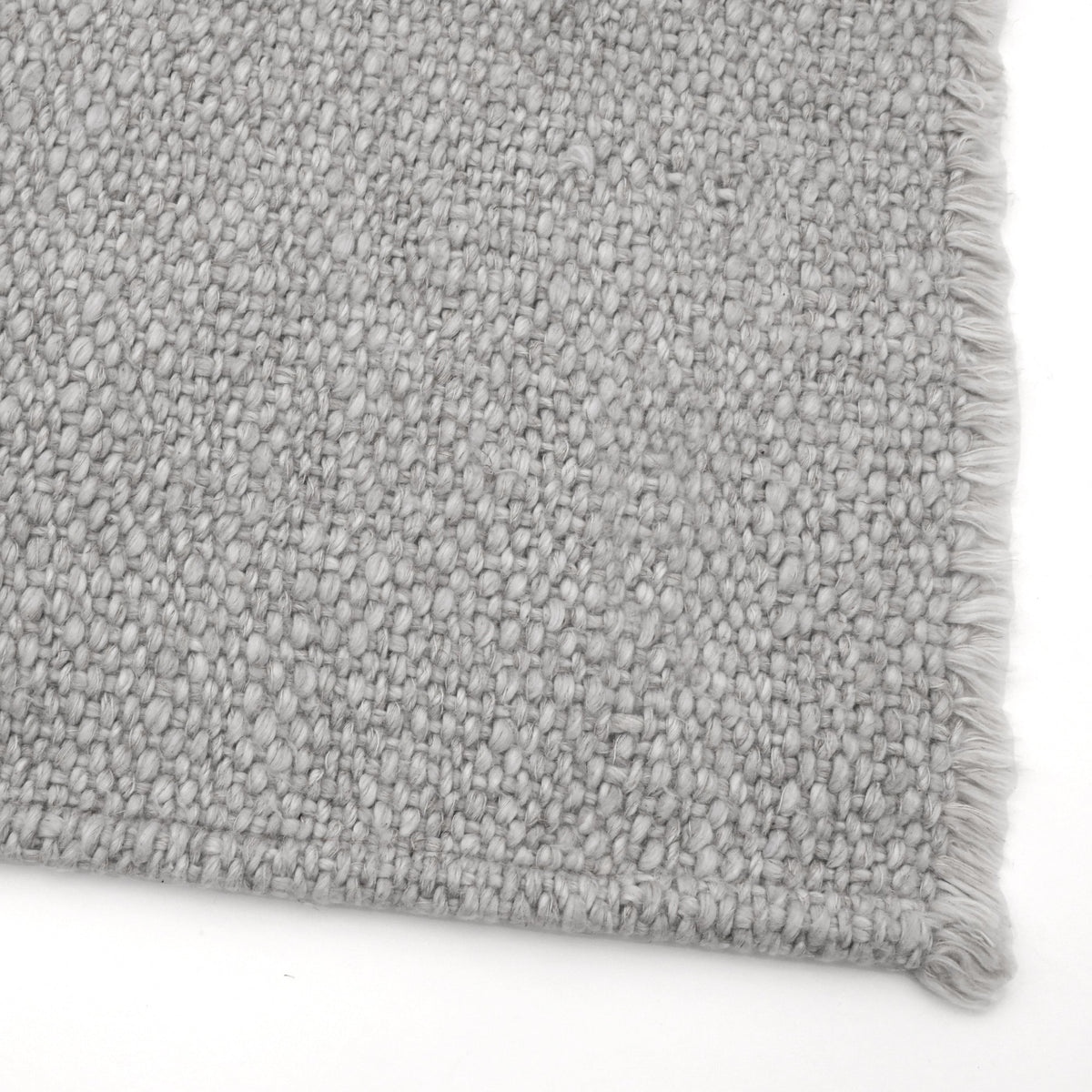 Light grey placemat close-up with woven texture and frayed fringed border