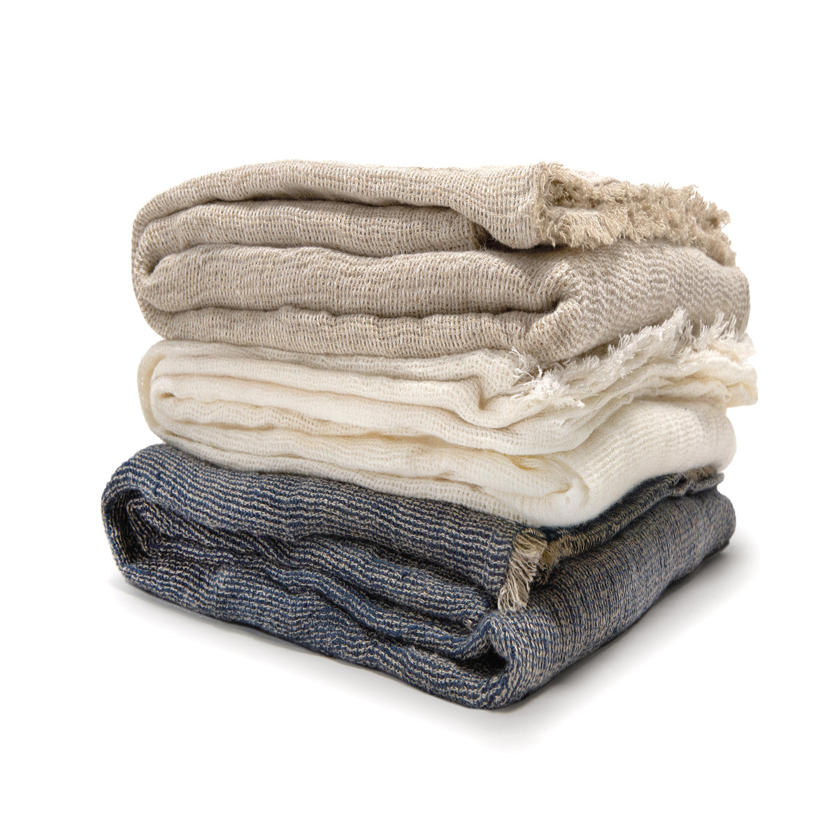 Oversized knit throw blanket in navy, cream, and natural tones with fringed edges on a white background.