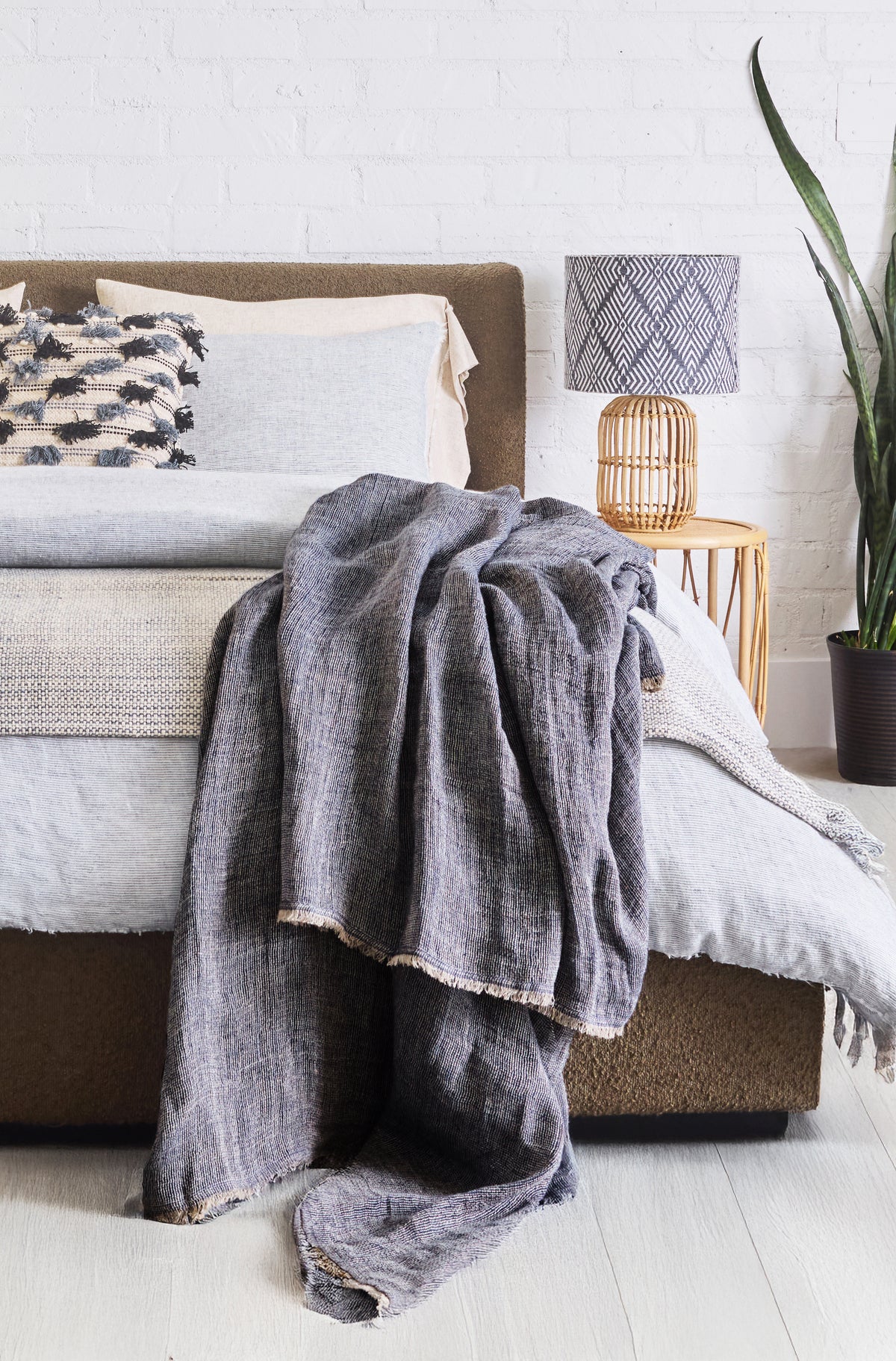 Gray oversized throw blanket with fringe draped over bed