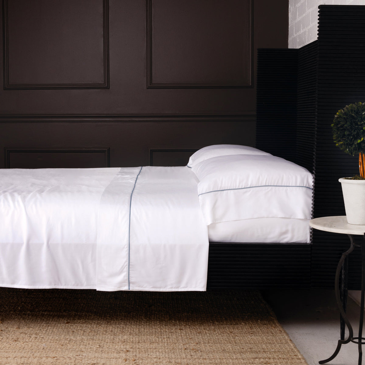 White sheet set with dark contrast piping, neatly fitted on mattress
