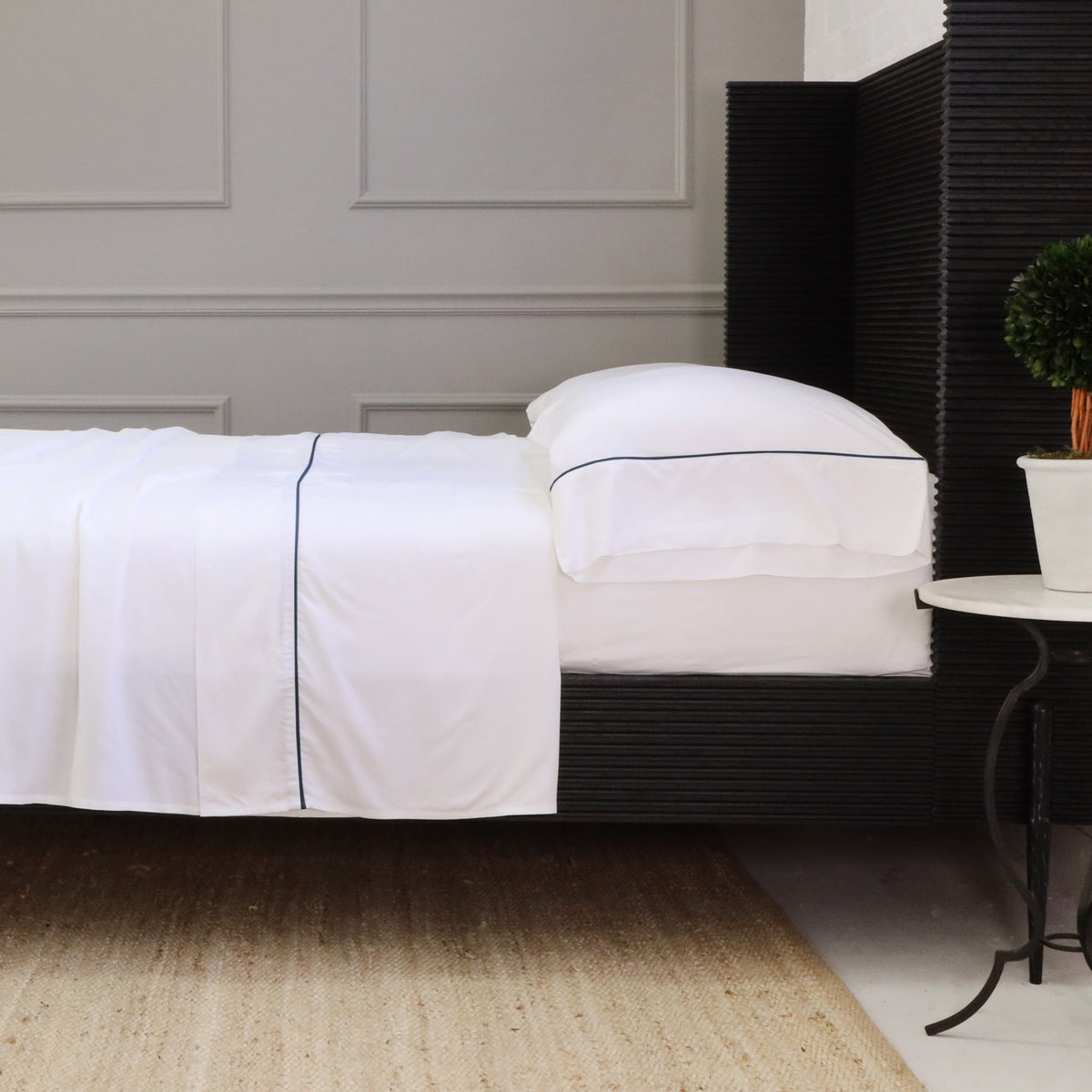 White sheet set with navy-edged seam lines on fitted sheet and pillowcase