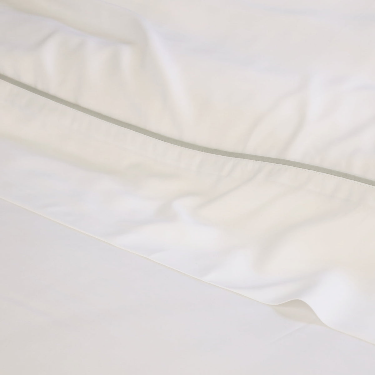 White bamboo sateen sheet fabric close-up with smooth sheen and stitched seam