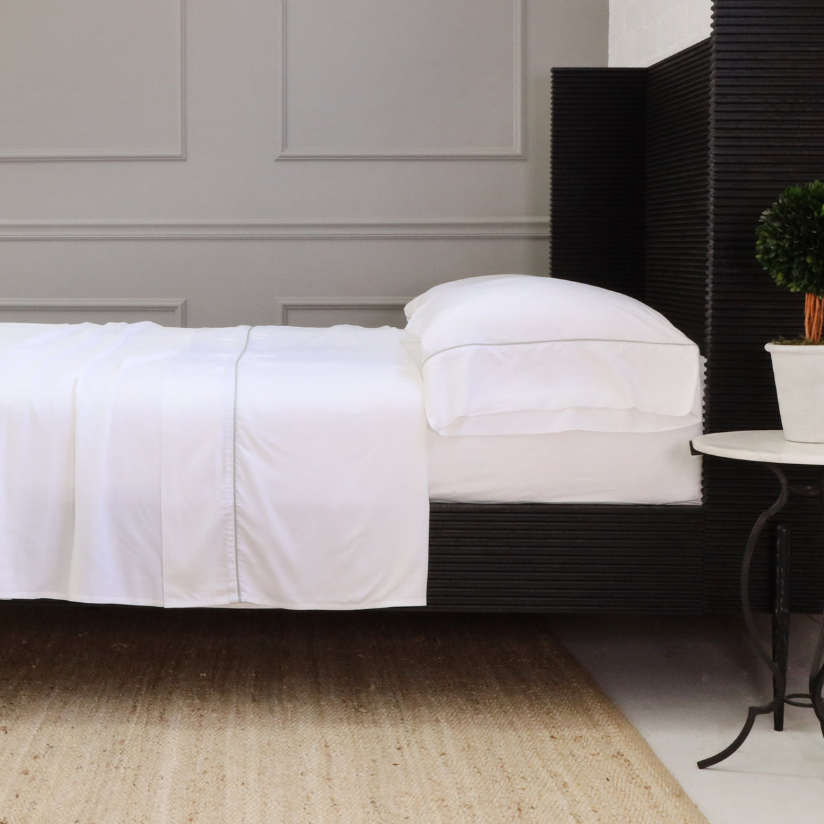 White sheet set with fitted sheet and folded pillowcases stacked on a bed