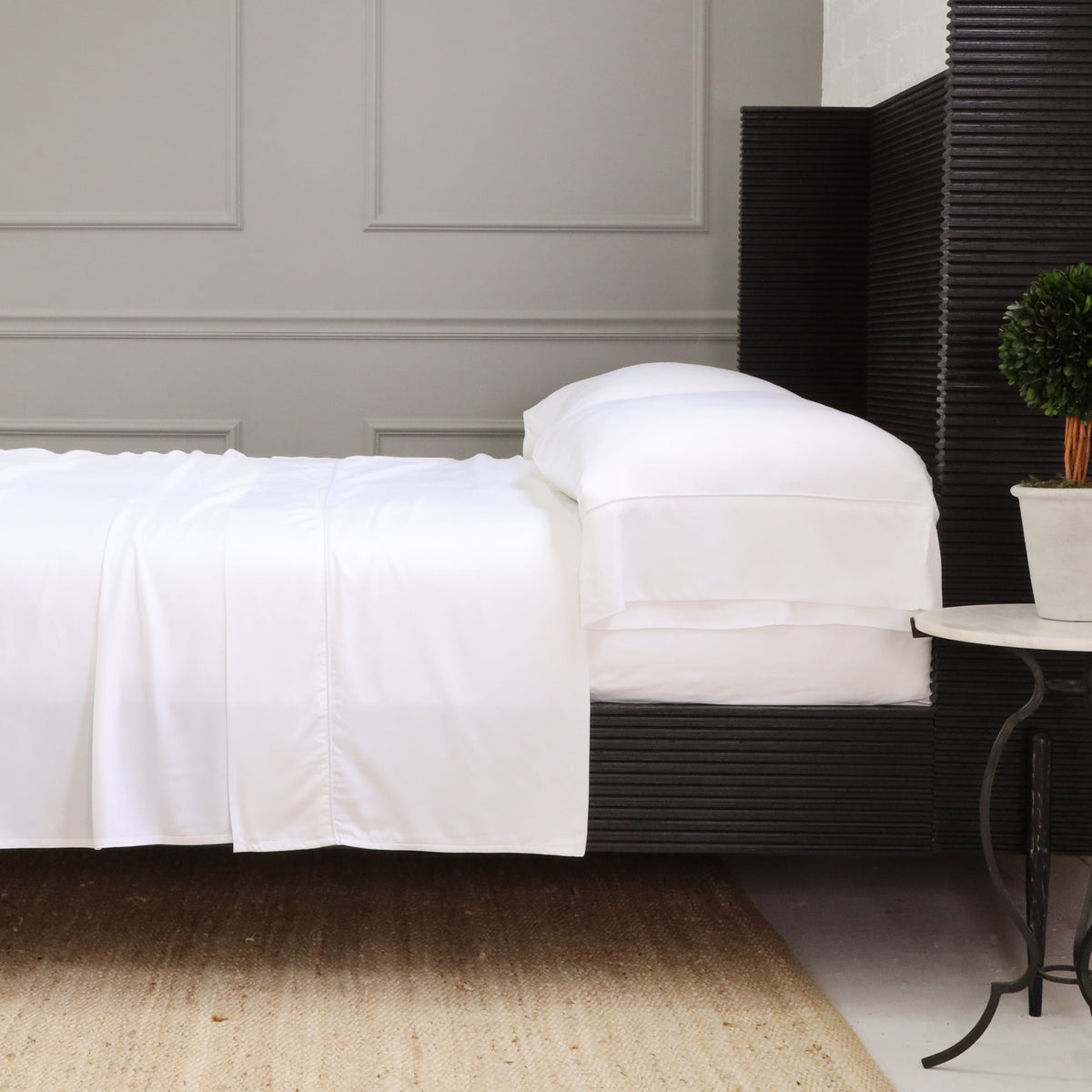 White sheet set with fitted and flat sheets and folded pillowcases on a bed