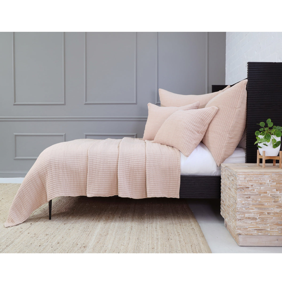 Natural tan textured coverlet set on bed with stacked pillows